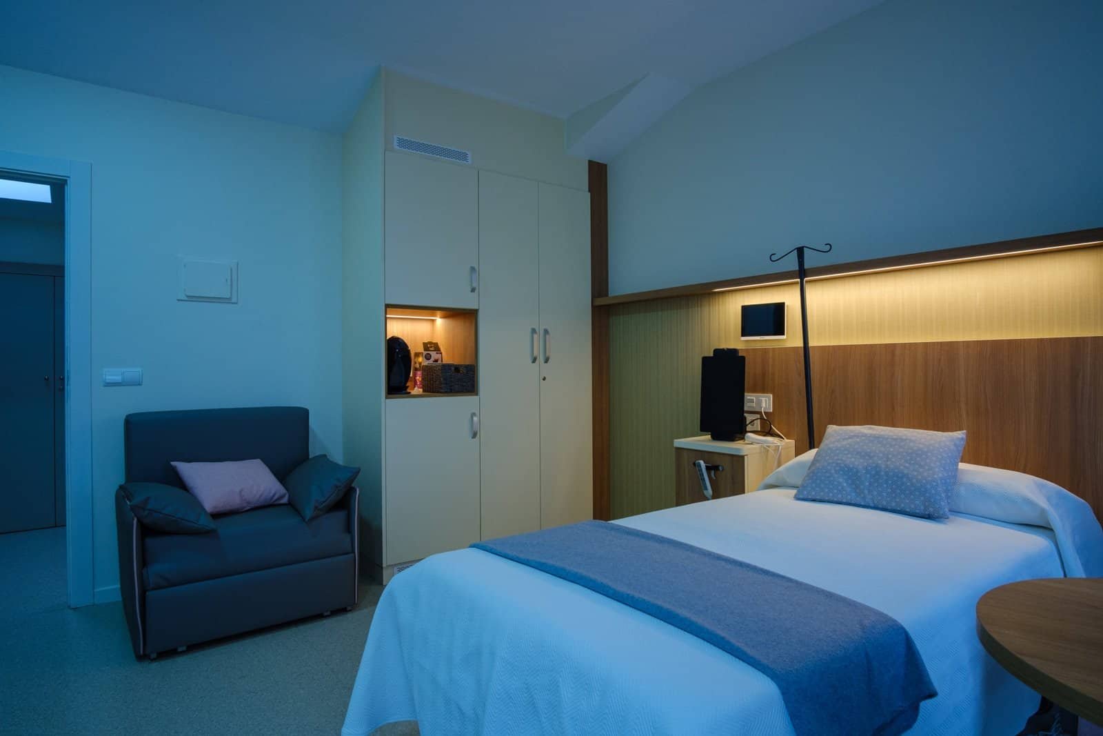Habitación individual en la residencia Colisée Miñano, equipada con cama articulada, sillón de acompañante y mobiliario funcional en un ambiente acogedor.