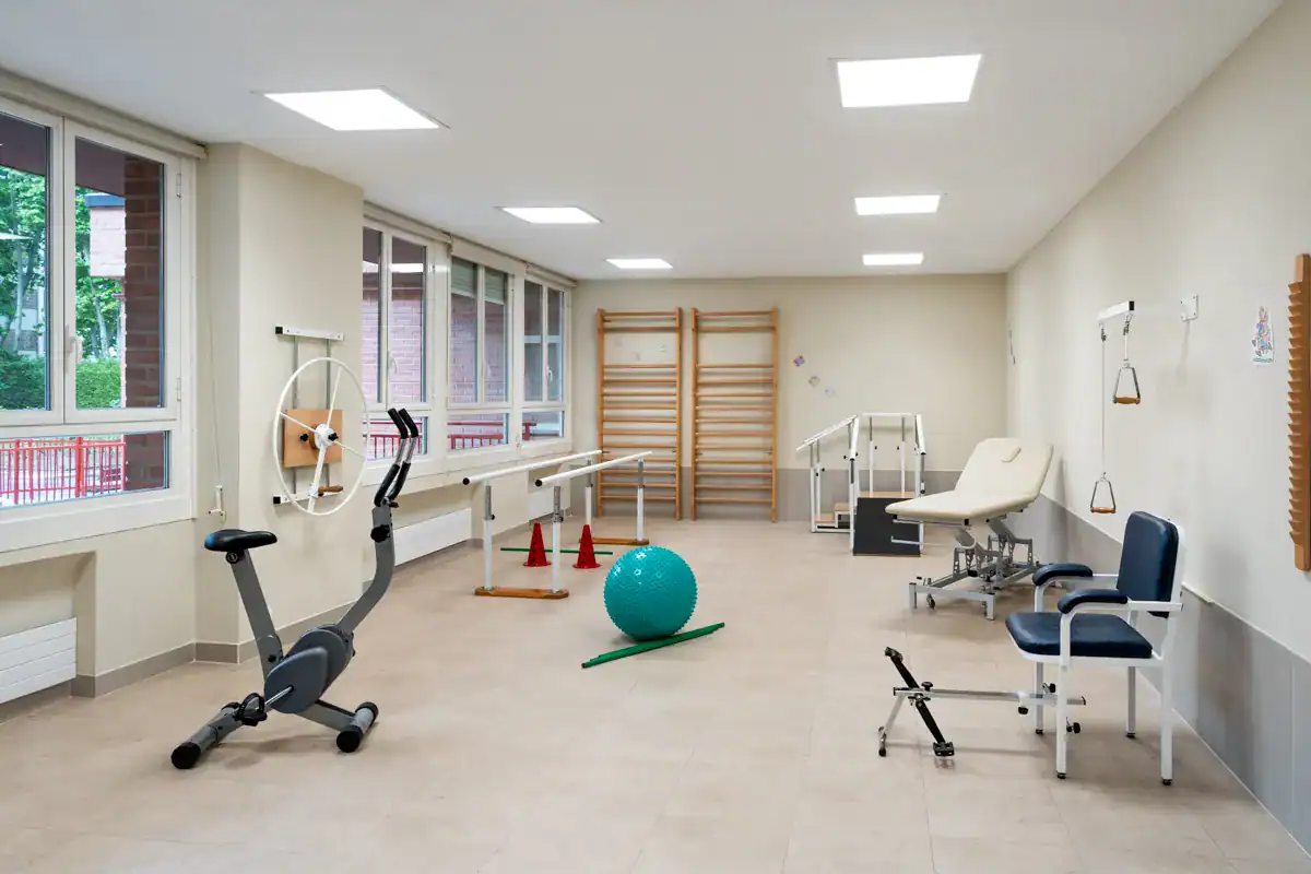 Sala de fisioterapia de la residencia DomusVi Gazalbide, equipada con bicicleta estática, espalderas, camilla y material de rehabilitación.