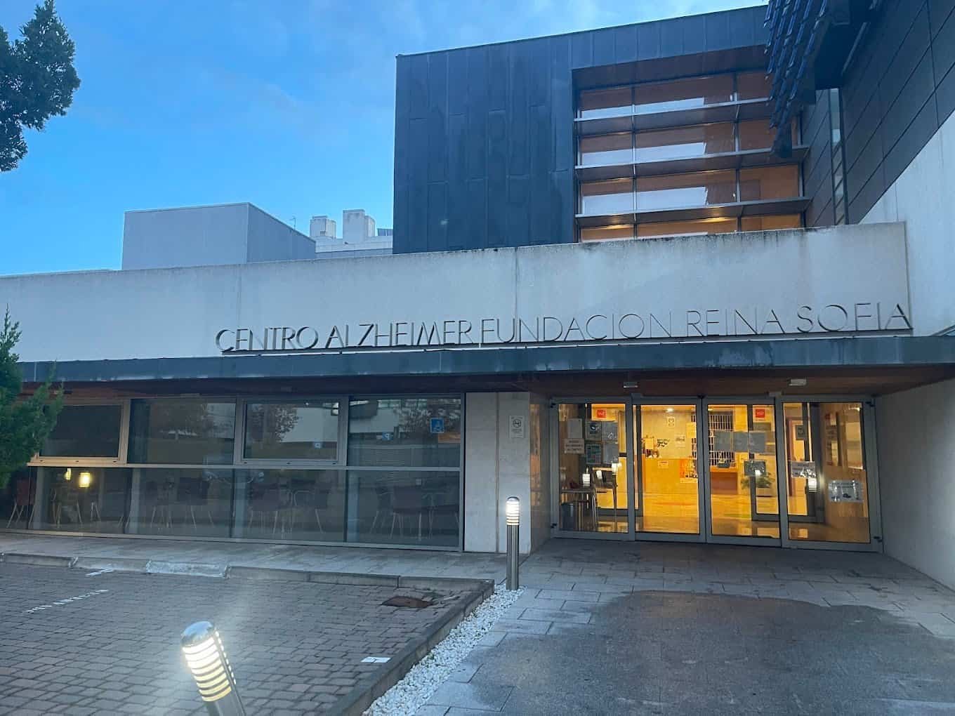 Fachada exterior del Centro Alzheimer Fundación Reina Sofía, un edificio moderno de color gris con ventanales y un gran letrero con el nombre del centro.