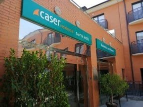 Fachada exterior de Caser Residencial Santo Ángel, un edificio moderno de varios pisos rodeado de un jardín.