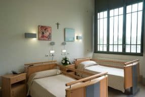 Sala de estar de la residencia con un sofá de cuero marrón y sillones de varios colores, con una gran ventana que ilumina el espacio.