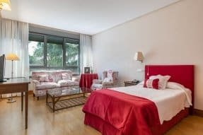 Dos residentes y una cuidadora sentados en un sofá en la sala de estar de la residencia, en un ambiente relajado y de compañía.