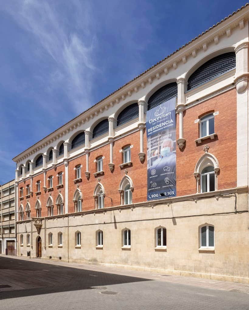 Fachada de la Residencia CleceVitam San Francisco, un edificio de ladrillo con ventanas de arco y un gran cartel con el nombre del centro.