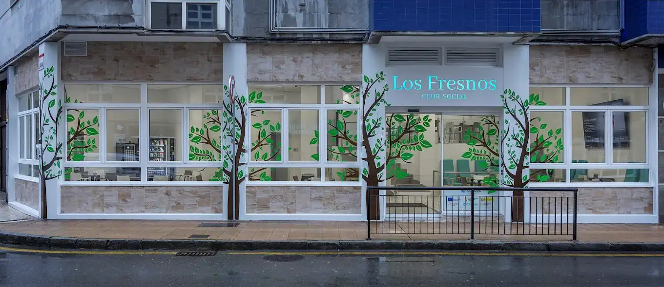 Fachada de la "Residencia Los Fresnos" con grandes ventanales decorados con vinilos de árboles, mostrando el interior.