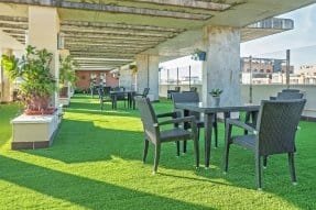 Terraza exterior con césped artificial, mesas y sillas, ideal para actividades al aire libre en la residencia Bouco Córdoba Centro.