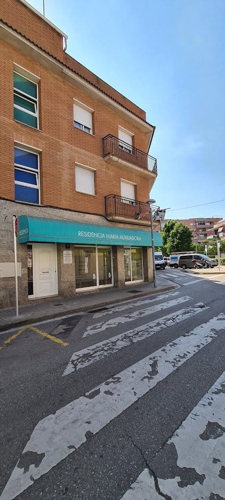 Fachada de la Residencia María Auxiliadora, edificio de ladrillo con toldo azul en la entrada, situada en una esquina urbana.
