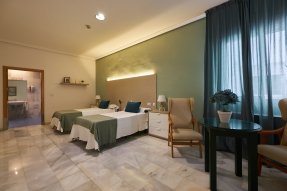 Habitación doble luminosa en la residencia, con dos camas y un baño completo en la misma estancia.