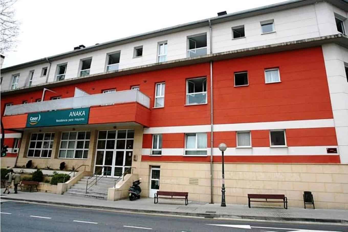 Fachada de un edificio de varias plantas, con los colores blanco y naranja, y el letrero de "Residencia para mayores" en un lateral.