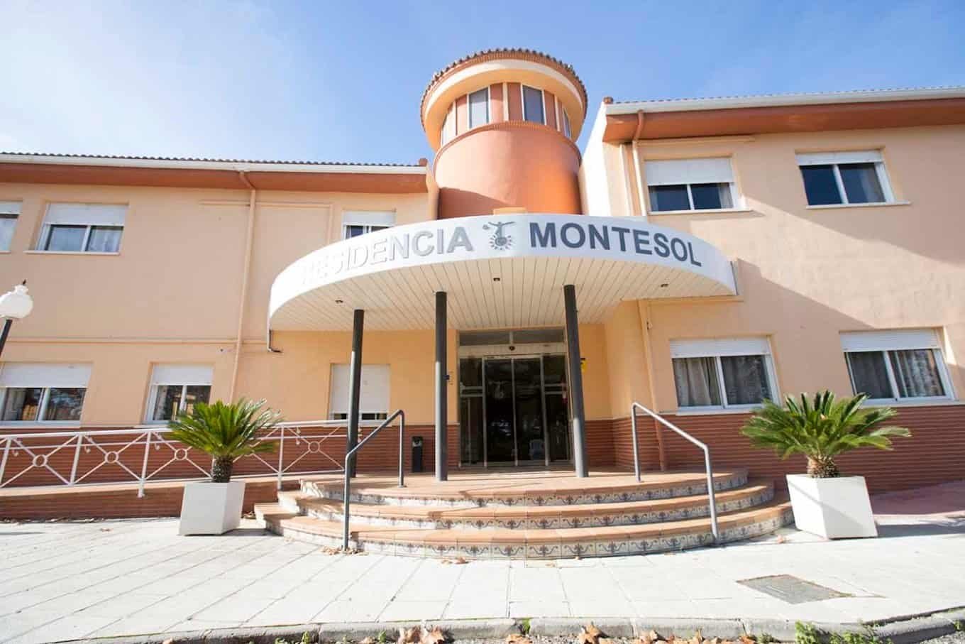 Fachada de un edificio de color beige con un porche de entrada con columnas, el nombre "Residencia Montesol" y una torre redonda.