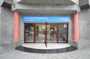 Entrada principal de un edificio con puertas de cristal y un letrero que dice "Centro Residencial El Palmeral".