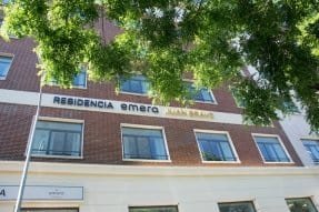 Edificio de ladrillo con un letrero que dice "RESIDENCIA emera JUAN BRAVO".