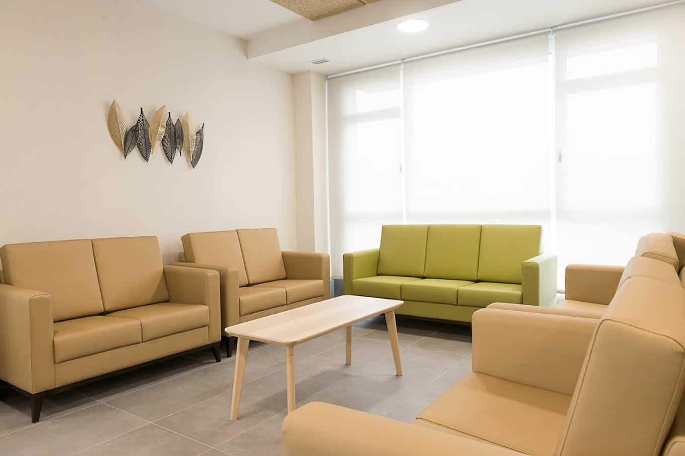 Sala de estar con sofás y sillones de color beige, una chimenea, un cuadro en la pared y una lámpara de pie.