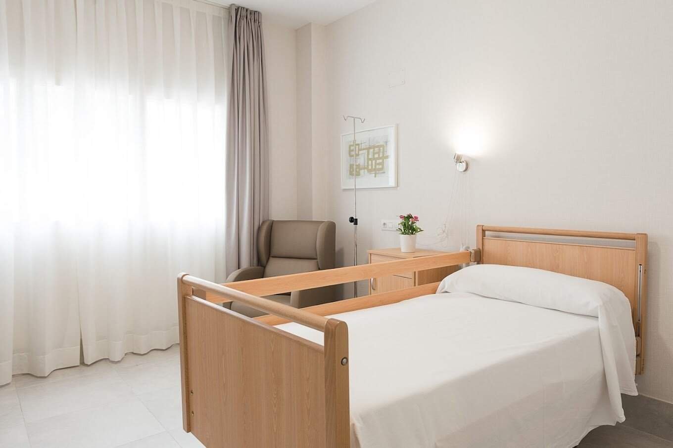 Habitación con dos camas, una mesilla de noche en el centro, dos sillones rojos y un televisor en la pared.