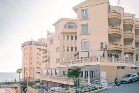 Fachada exterior de la residencia y centro de día Bouco El Campello, un edificio moderno con paneles de colores claros y un gran letrero con su nombre.